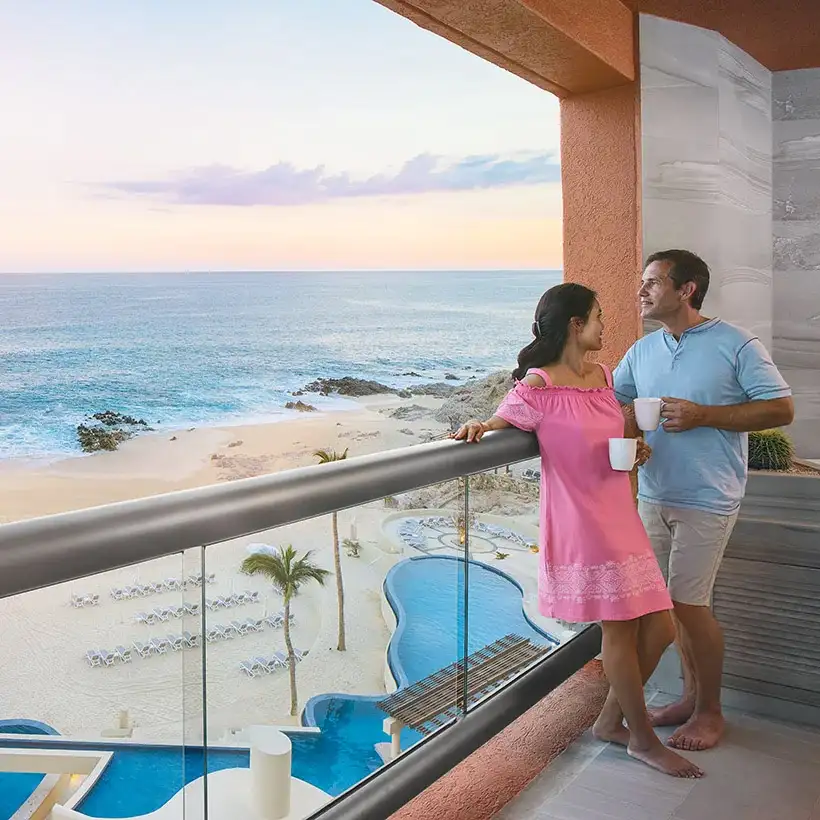 Couple drinking coffee on the balcony overlooking the pool and beach